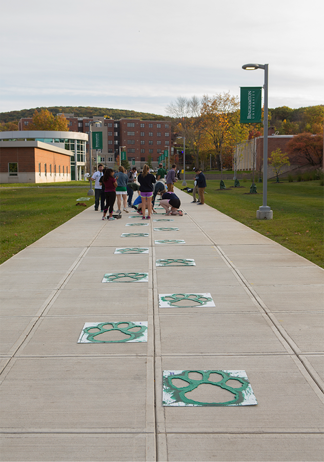 Students paint a sidewalk at SUNY Binghamton